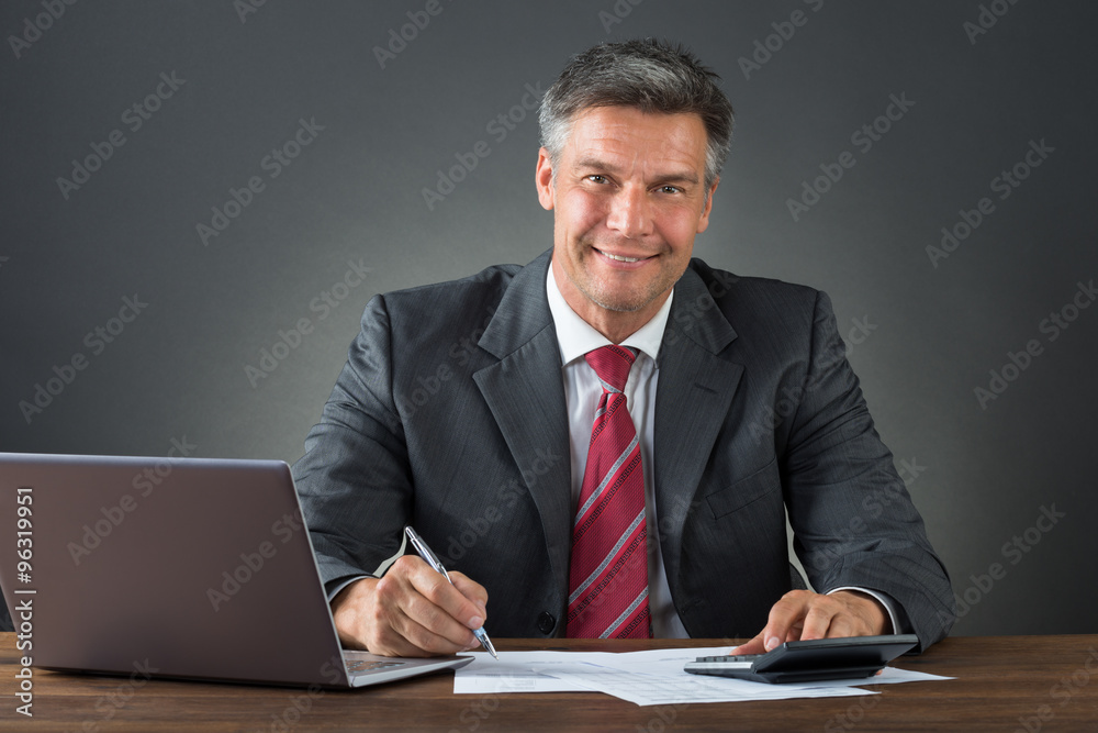 Businessman Checking Bills At Desk Businessman Checking Bills At Desk