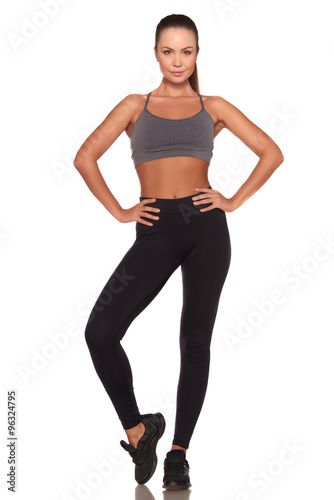 Fitness woman in sport style standing against isolated white background