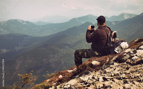 Traveler with binoculars sitting on top of a mountain
