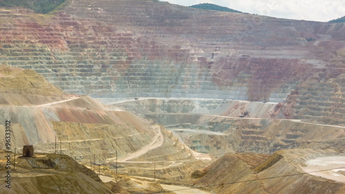 Wide angle time-lapse of open pit copper mine. Mountain carved into terraces for mining, with dump trucks driving and speeded up clouds photo