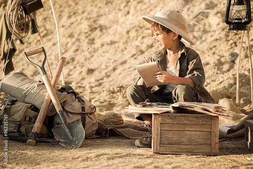 Fotografie Boy archaeologist take notes in a notebook on the excavations conducted