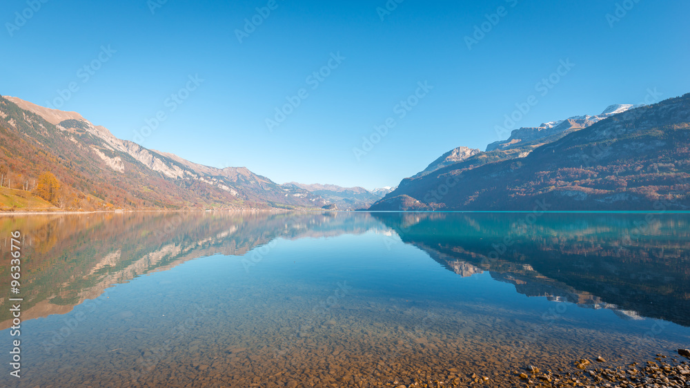 Autumn landscape of a mountain lake. In the clear water visible stones on the bottom. 