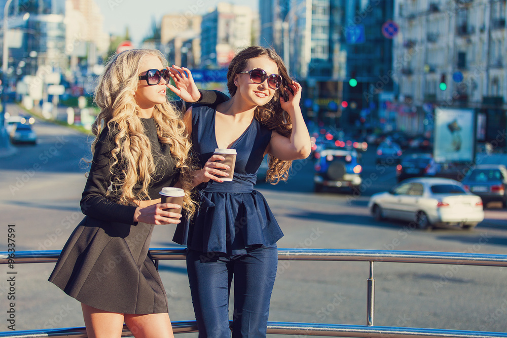 Lifestyle portrait of two best friends girls spending time in the center of the city at nice summer day, trendy fashion looks