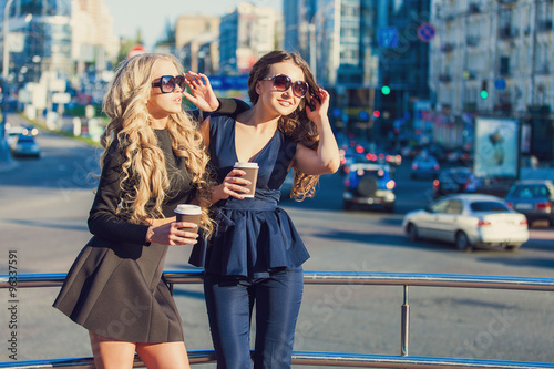 Lifestyle portrait of two best friends girls spending time in the center of the city at nice summer day, trendy fashion looks