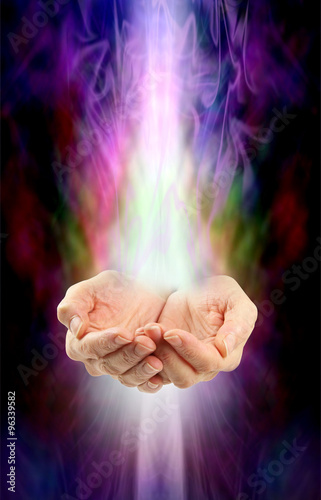 Receiving healing - Female cupped hands with white energy streaming in from above and below on a swirling misty multicolored ethereal energy background