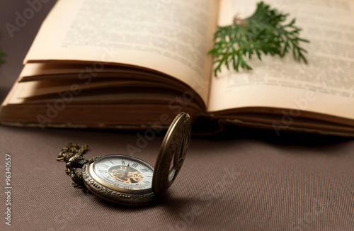 Old pocket watch with an opened book