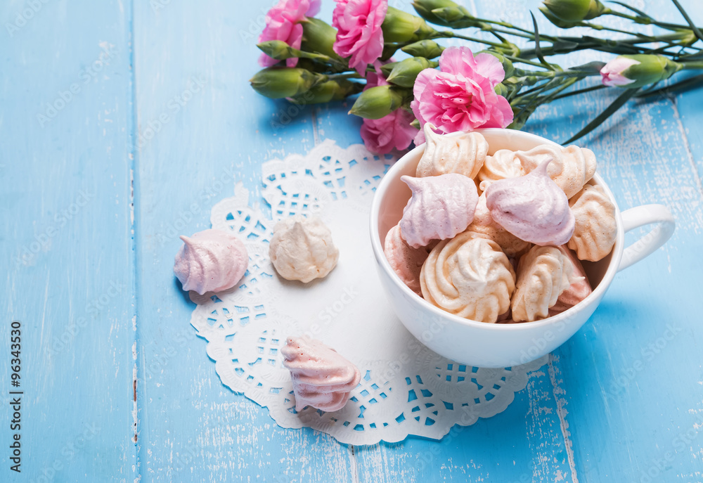 Meringues in the cup and pink flowers on the table close-up Meringues in the cup and pink flowers on the table close-up