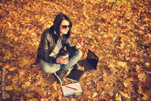 hipster girl sitting on the leaves in the park