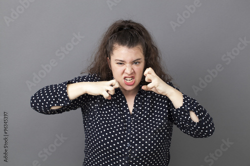 female fighting concept - angry 20s big woman showing childish anger and aggressiveness for teen rebellion or intimidation,studio shot photo