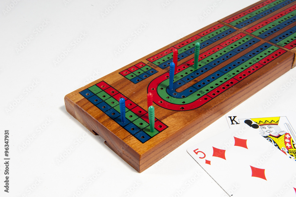 Cribbage board with red, green and blue pegs against a white background
