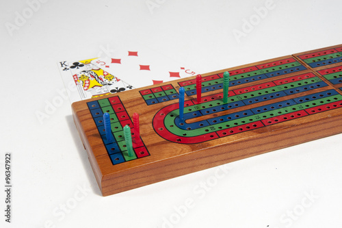 Cribbage board with red, green and blue pegs against a white background