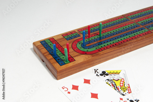 Cribbage board with red, green and blue pegs against a white background