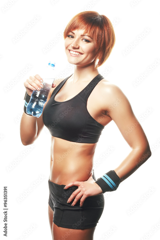 Young fit woman standing and looking at camera with bottle of wa Young fit woman standing and looking at camera with bottle of wa