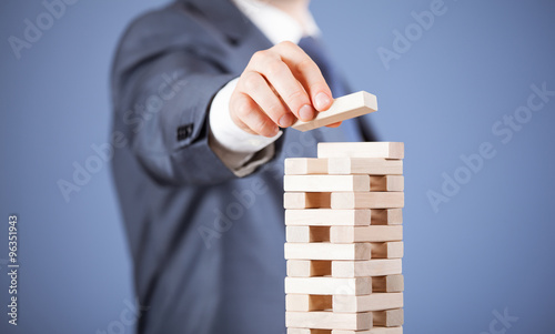 Unrecognizable businessman forming a wooden pyramid