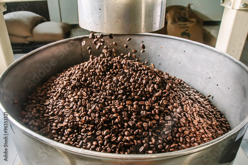 The freshly roasted coffee beans from a coffee roaster being poured into the tank.