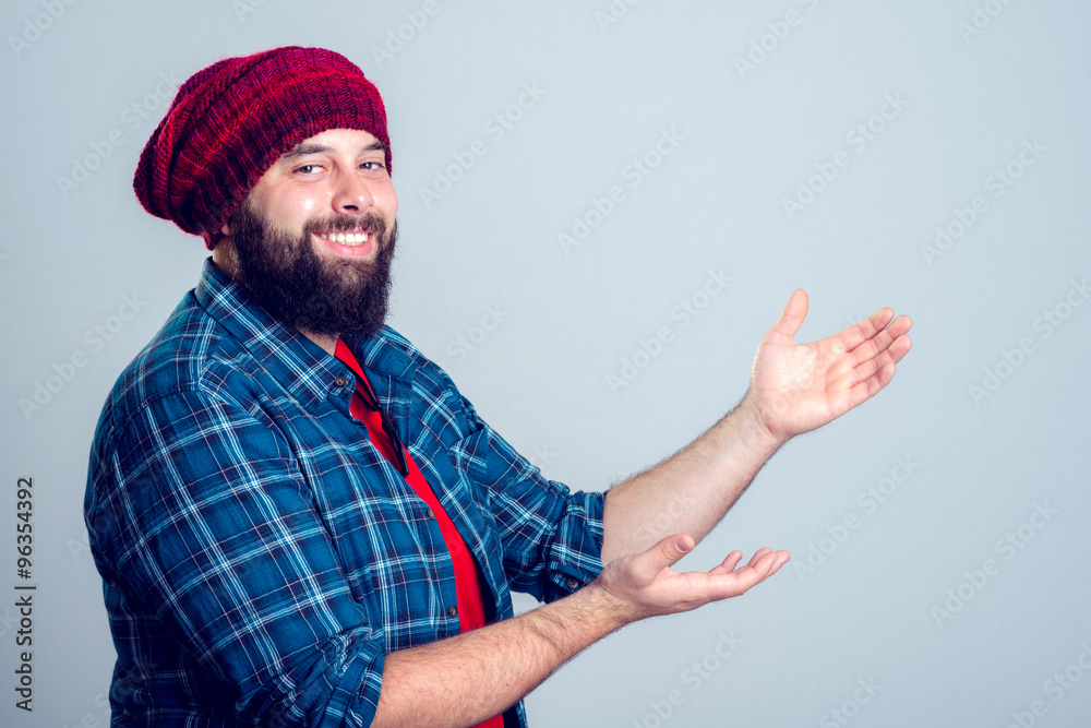 Naklejka premium bearded man with woolen cap is pointing to the side