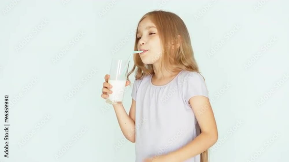Satisfied child drinking milk. Stroking tummy. Girl with beautiful blonde hair on a white background. Thumb up. Ok Satisfied child drinking milk. Stroking tummy. Girl with beautiful blonde hair on a white background. Thumb up. Ok
