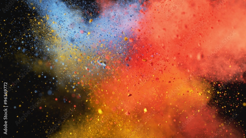 Red, yellow and blue powder/particles fly after being exploded against black background. Shot with high speed camera, phantom flex 4K. 4K 30fps. Slow Motion.
