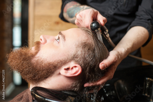 Professional male hairdresser is cleaning human head