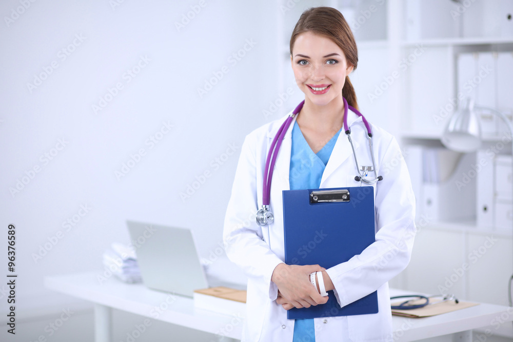 Smiling female doctor with a folder in uniform standing at hosp Smiling female doctor with a folder in uniform standing at hosp