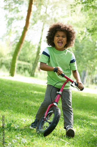 Fototapeta Naklejka Na Ścianę i Meble -  Young Boy Learning To Ride Bike In Park