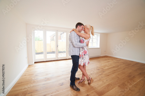 Excited Young Couple In Empty Room Of New Home