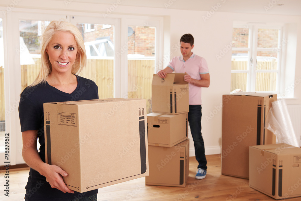Young Couple Unpacking Boxes In New Home Young Couple Unpacking Boxes In New Home
