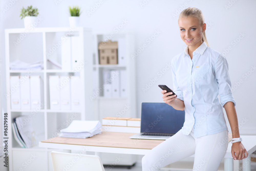 Businesswoman sending message with smartphone sitting in the of