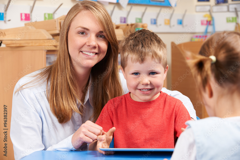 Teacher Helping Elementary Scool Pupil To Use Digital Tablet Teacher Helping Elementary Scool Pupil To Use Digital Tablet