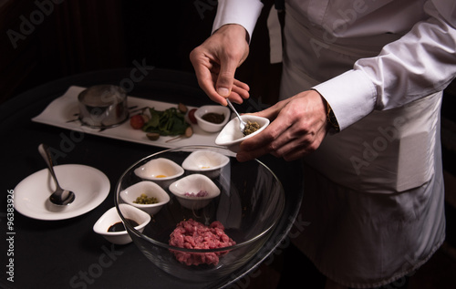 Chef prepares a delicious tartare, all the ingredients on the table next to