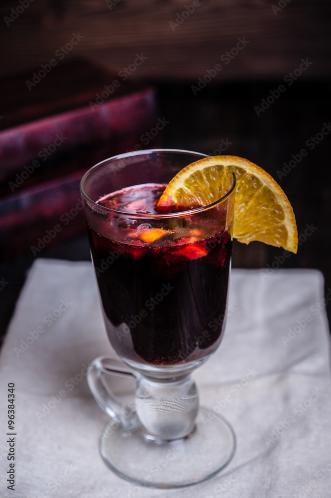 A glass of mulled wine and a slice of orange is on the table A glass of mulled wine and a slice of orange is on the table