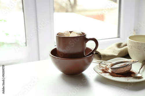 Cup of coffee with marsh mellow on a table in kitchen