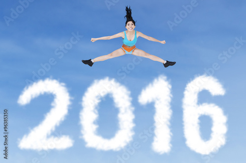 Healthy woman jumping above numbers 2016