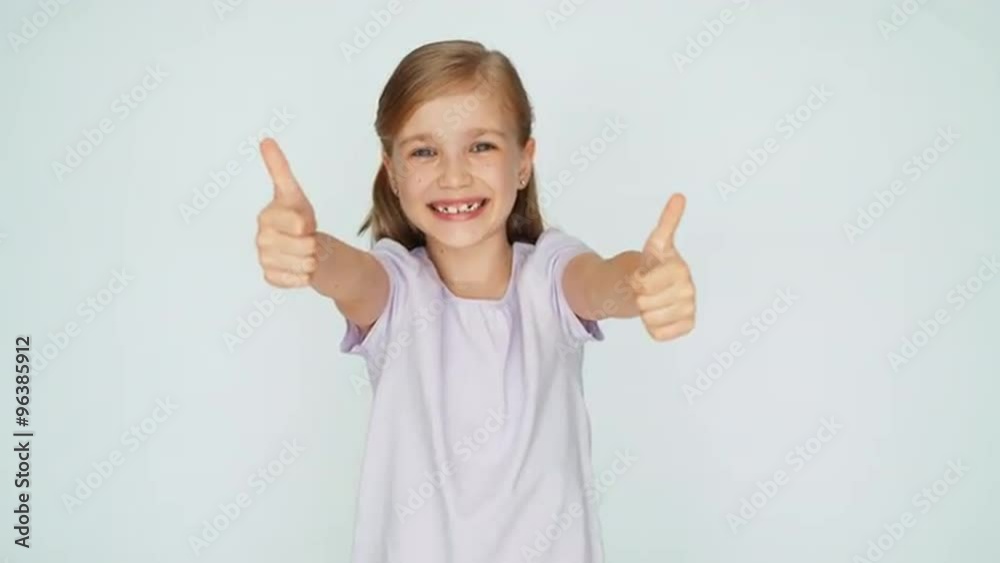 Thumbs up. Ok. Girl laughing at camera. Child is on the white background Thumbs up. Ok. Girl laughing at camera. Child is on the white background