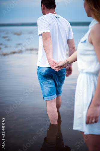 Young man and woman holding hands are in water