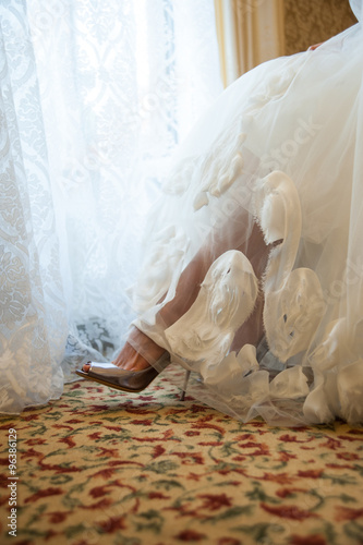 Legs of the bride in silver shoes visible from under the dress