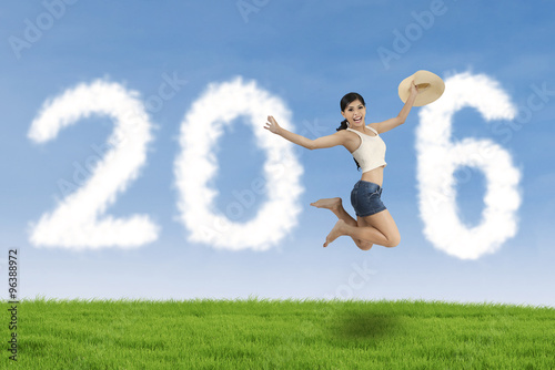 Young woman jumping at field with numbers 2016
