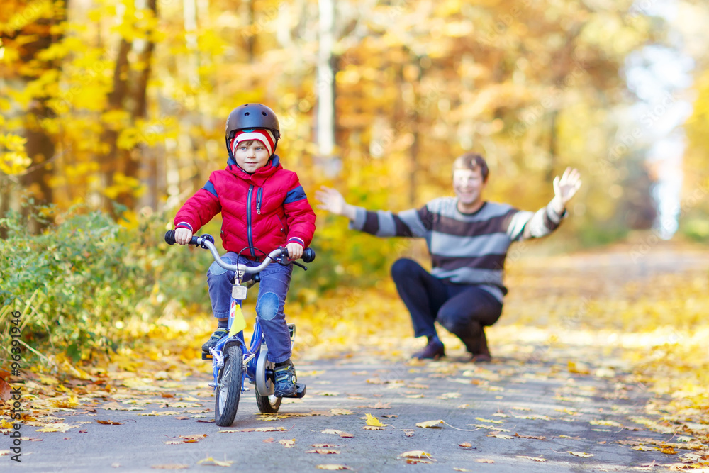 Fototapeta premium Little kid boy and father with bicycle in autumn forest