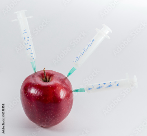 Apple in a medical syringe on a gray background. Introduction to photo