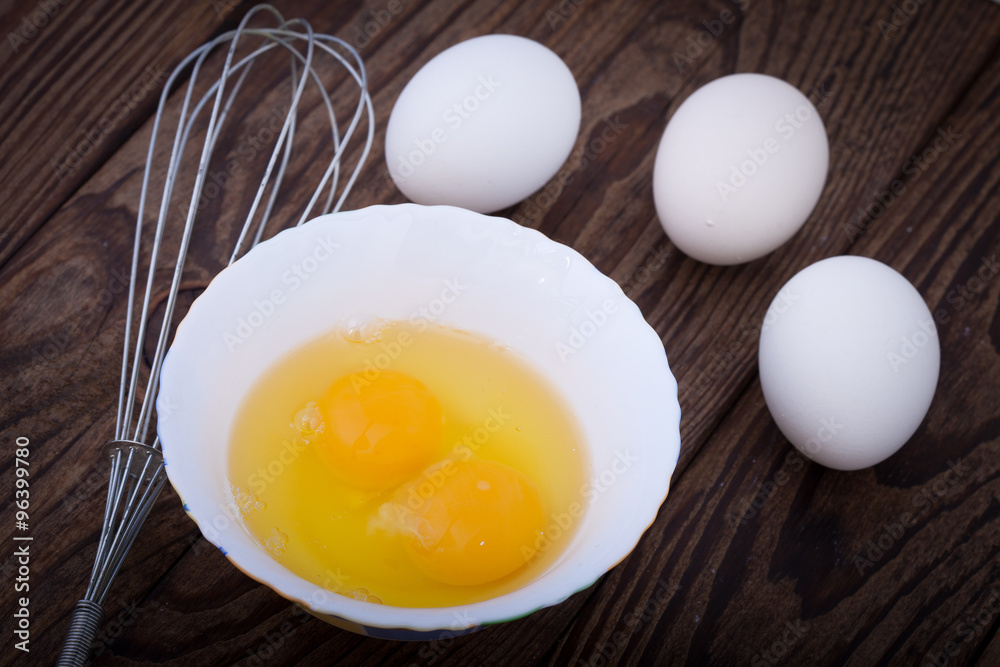 Raw eggs in bowl for whipping on wooden. Baking ingredients. Raw eggs in bowl for whipping on wooden. Baking ingredients.