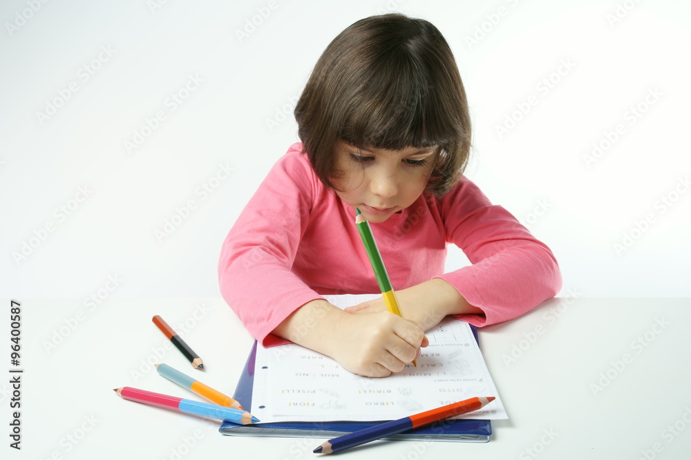 little girl is doing homework on a white background, dressing a pink shirt
little girl is doing homework on a white background, dressing a pink shirt
