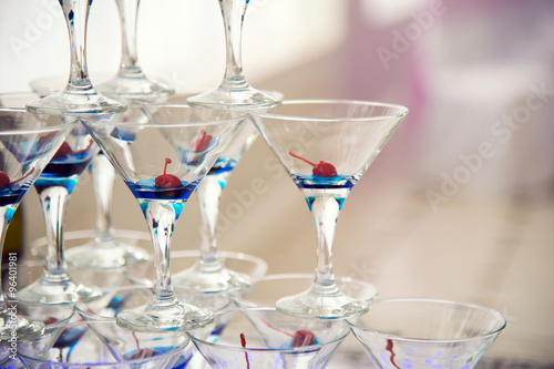 Glass goblets. Pyramid of champagne. The hill of glasses of wine and cherries. Glasses for alcohol. Festive drink. Bartender show. Decorations for the Banquet.