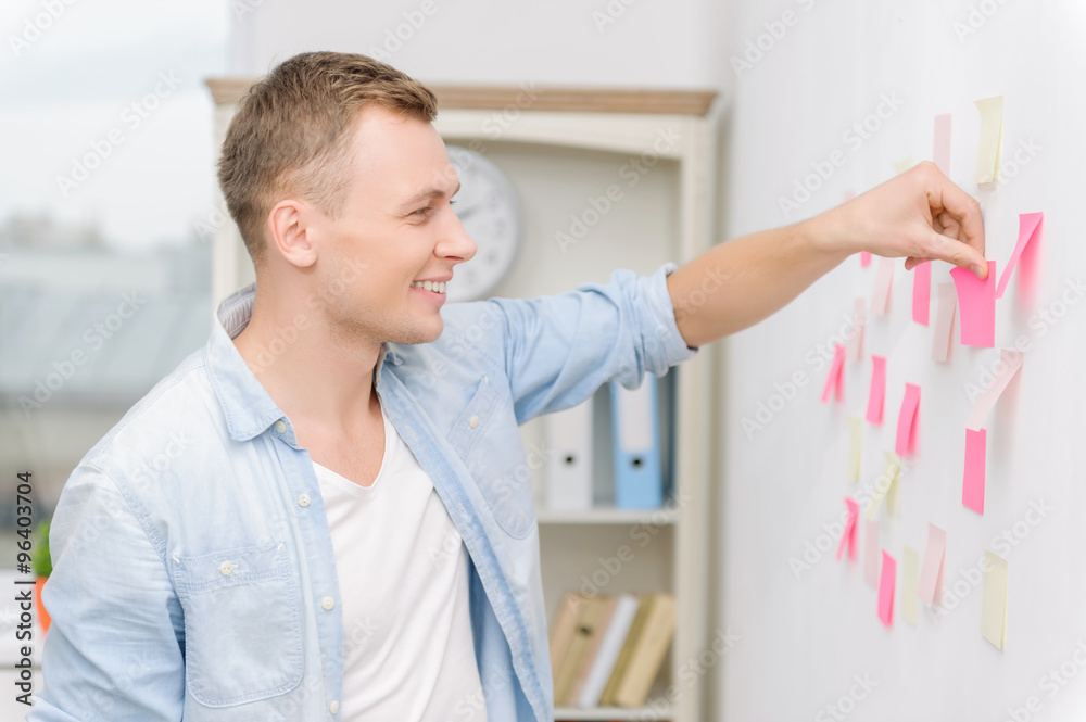 Fototapeta premium Workman attaching post-it notes to the wall.