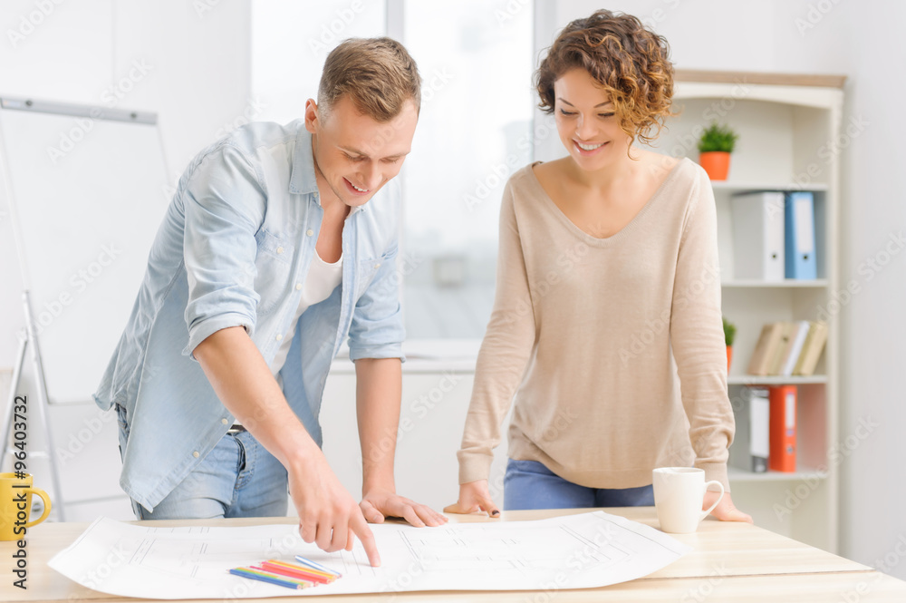 Two positive partners are collaborating over a drafting. Two positive partners are collaborating over a drafting.