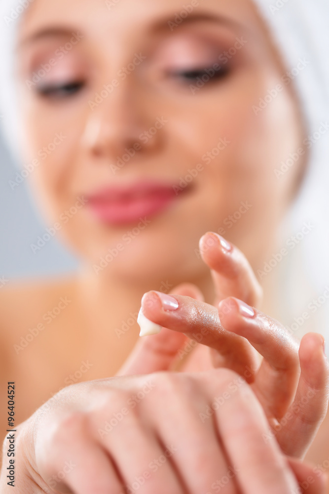 Young woman putting cream on her hand Isolated on gray background Young woman putting cream on her hand Isolated on gray background