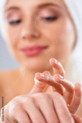 Young woman  putting cream on her hand Isolated on gray background