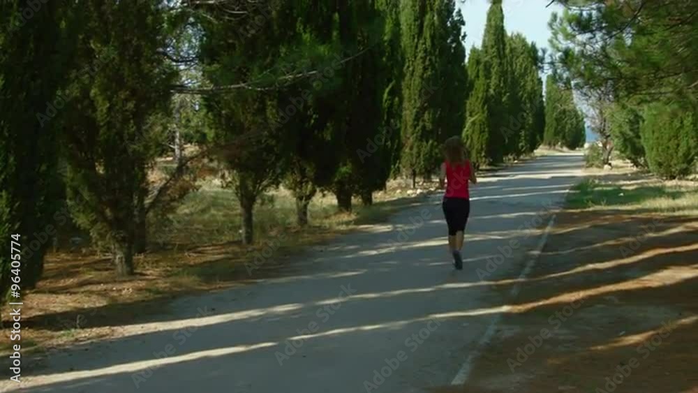 Young woman running in the park at the alley Young woman running in the park at the alley