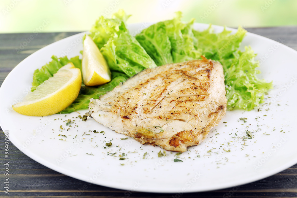 Dish of fish fillet with lettuce and lemon on table close up Dish of fish fillet with lettuce and lemon on table close up