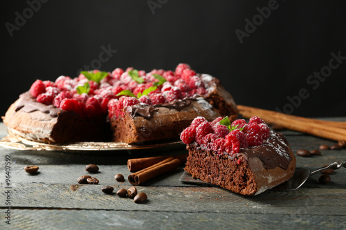 Cake with Chocolate Glaze and raspberries on tray on dark background