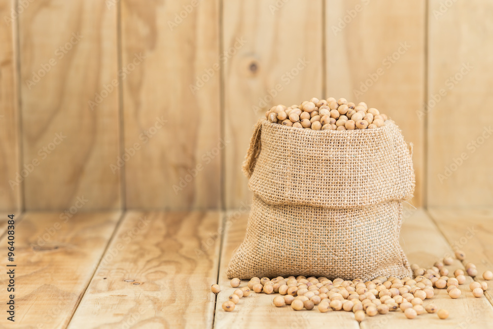 Fototapeta premium Soy beans in sack on wooden desk
